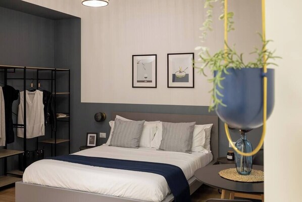 A modern bedroom with a bed, bedside tables, a wardrobe, and two framed pictures on the wall. - Trieste Chic Studio: Historic Elegance (Trieste)