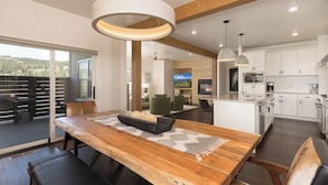 A modern kitchen with white cabinets, a central island, and a dining area with a wooden table and chairs.