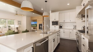A modern kitchen with white cabinetry, stainless steel appliances, and a large island with a sink.