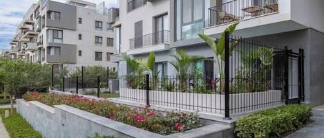 Un edificio de apartamentos moderno con balcones, un jardín ajardinado y un camino pavimentado.