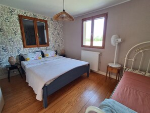 A bedroom with a bed, a radiator, a window, a bedside lamp, and a mirror.