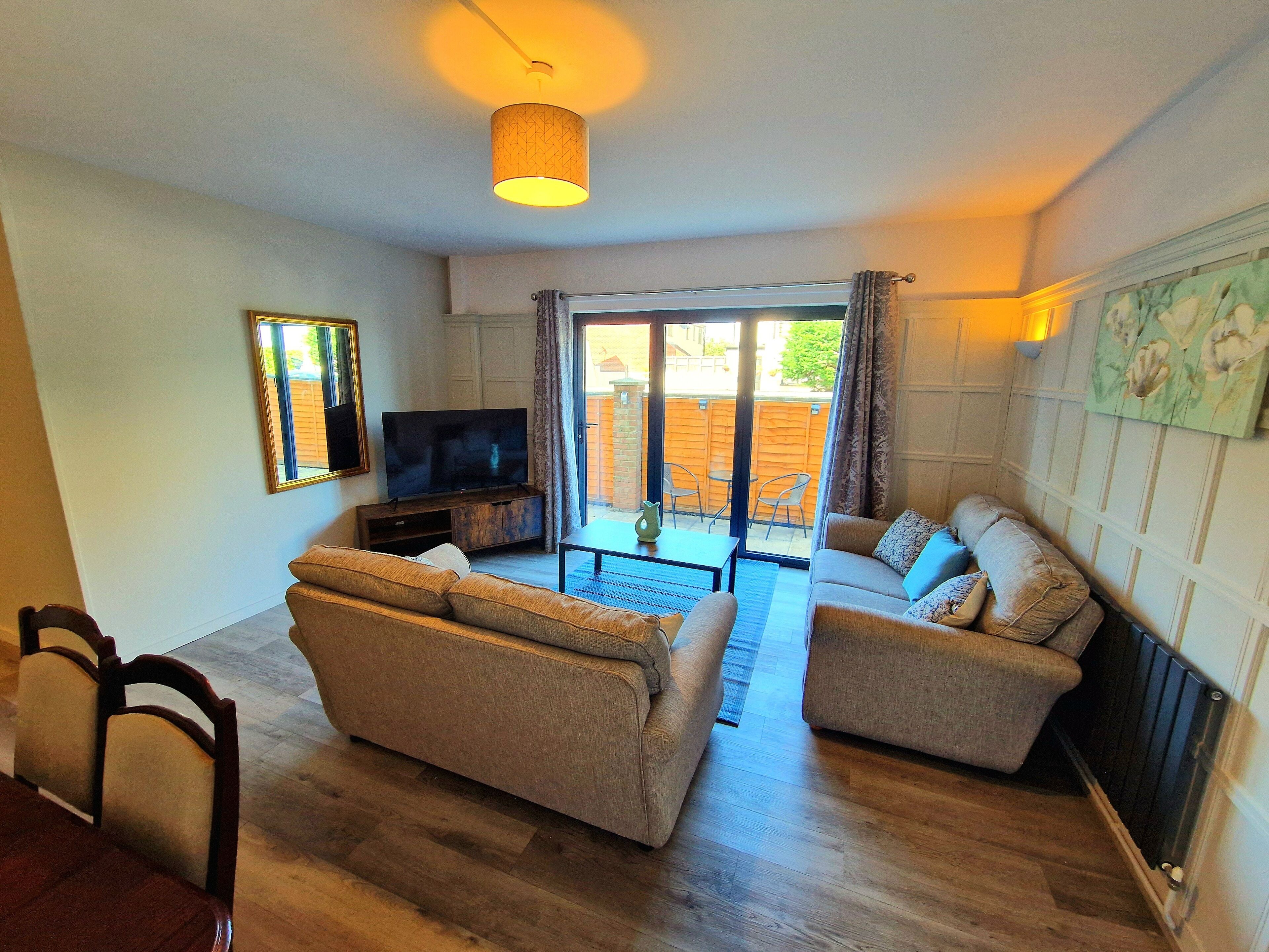 A living room with a sofa, a TV, and a dining area with chairs and a table.