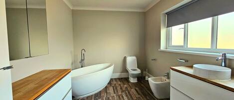 Un baño moderno con una bañera independiente, inodoro, bidé y lavamanos.