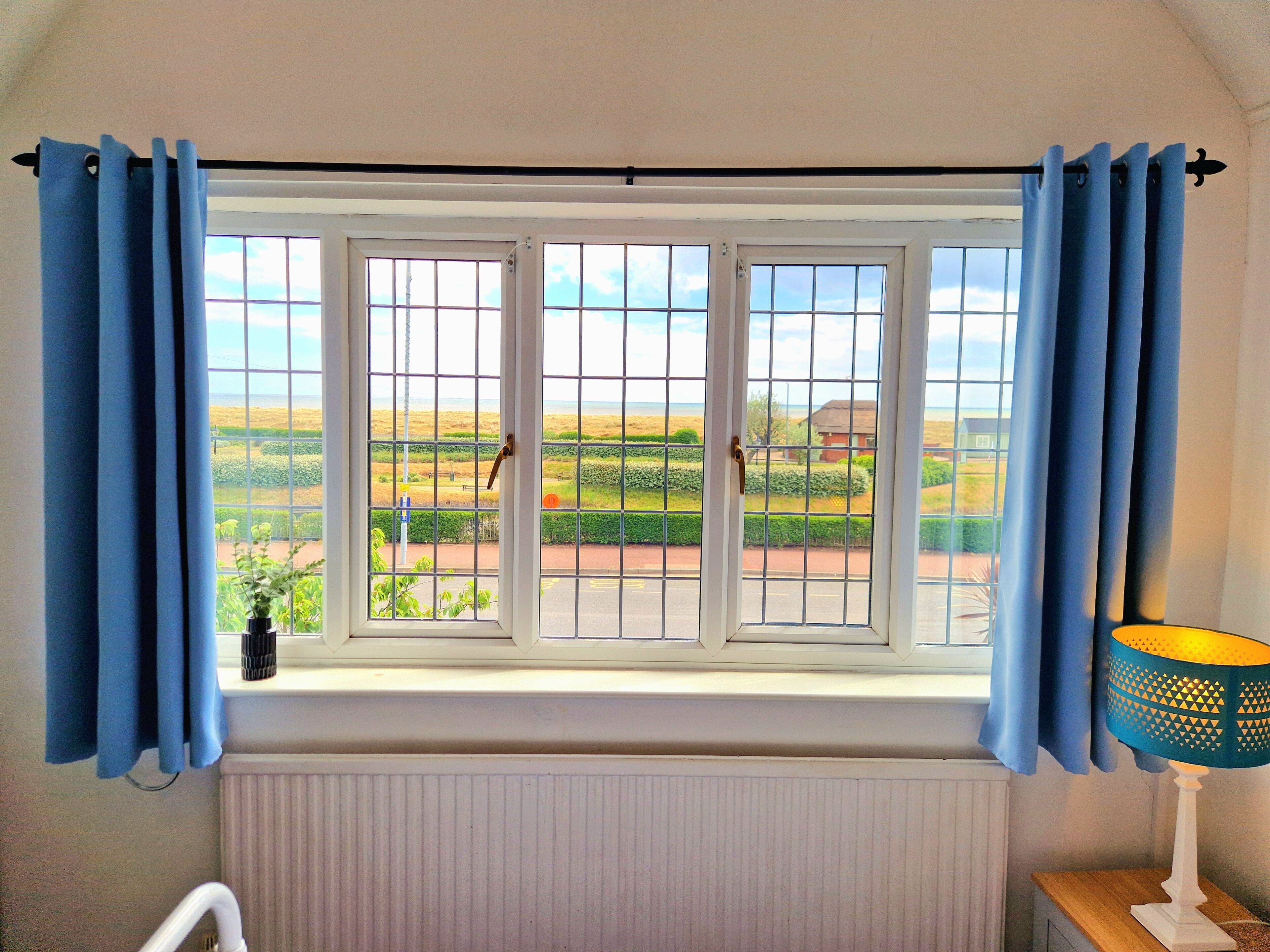 A room with a window overlooking a landscape, a radiator below, and a lamp on a bedside table.