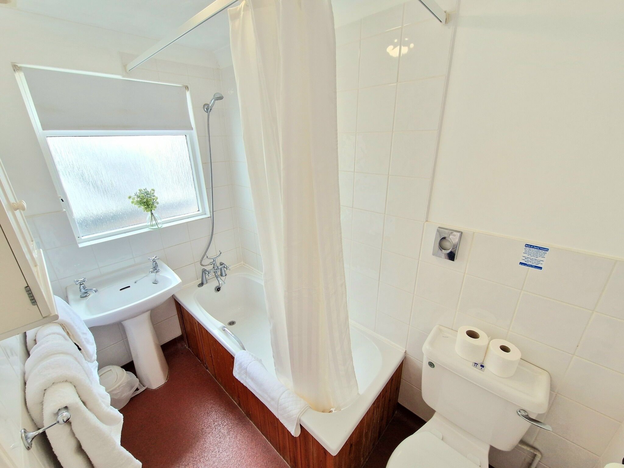 A bathroom with a bathtub, a sink, a toilet, and a window with a view.