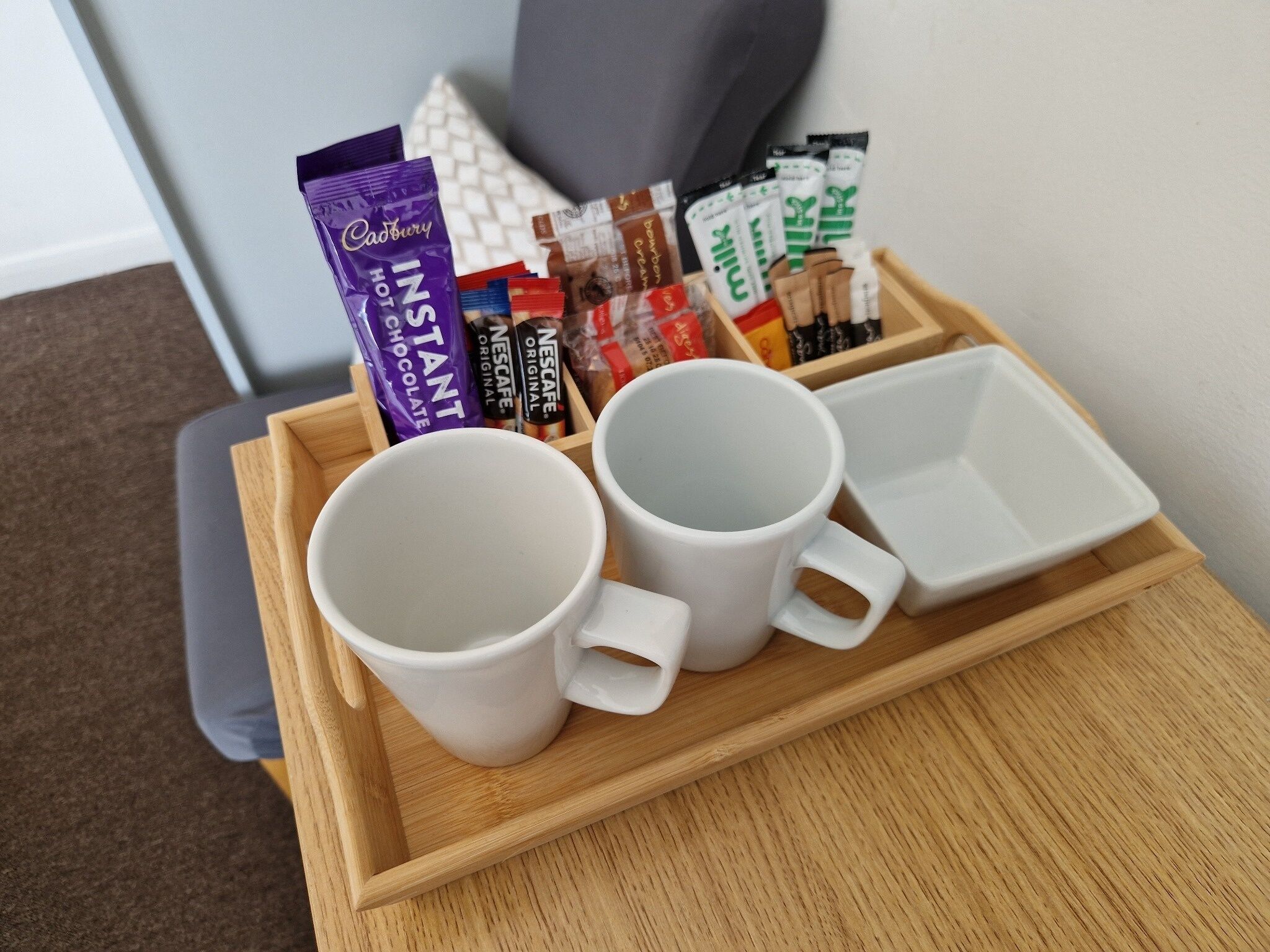A tray with two white mugs and a Cadbury hot instant chocolate bar.