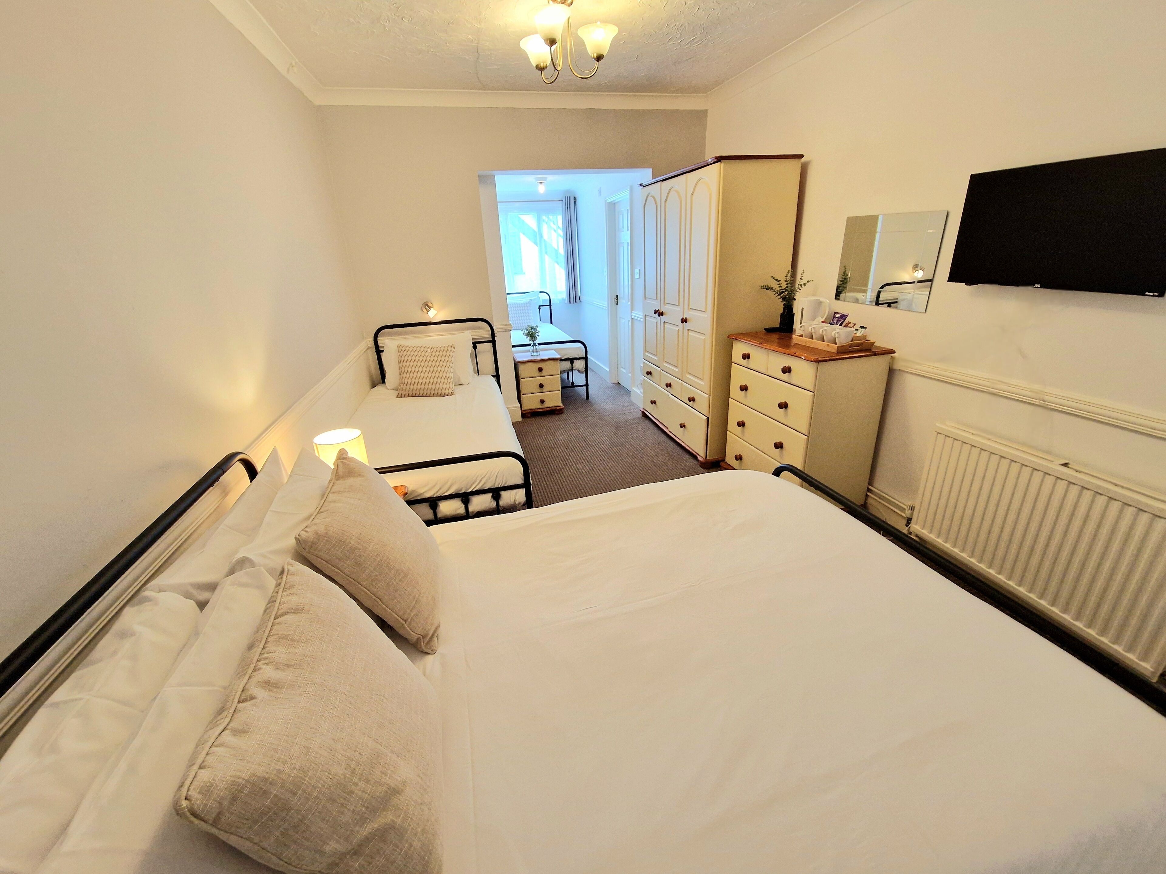 Ein Hotelzimmer mit einem großen Bett, einem Nachttisch, einem Schminktisch, einem Spiegel und einem Fernseher.