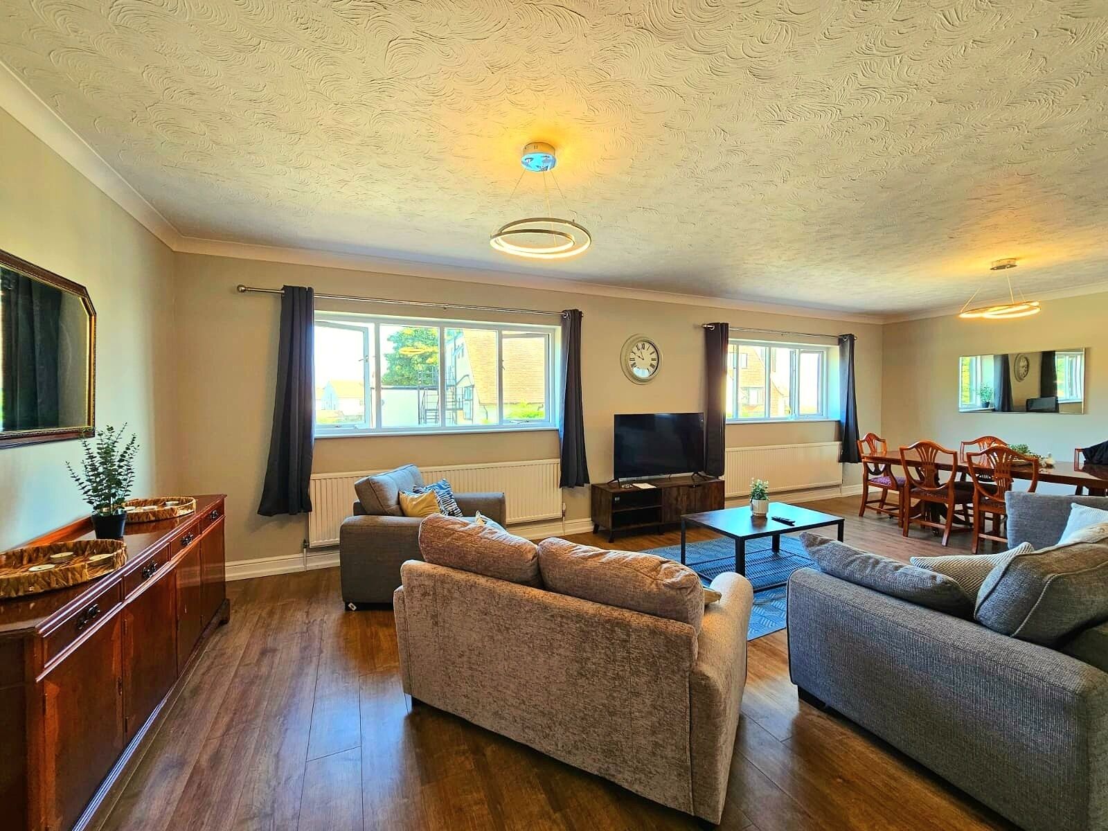 Ein Wohnzimmer mit einer Couch, einem Fernseher, einem Esstisch und Stühlen.