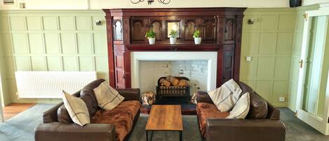 A living room with two brown leather sofas, a wooden coffee table, and a fireplace with decorative items.