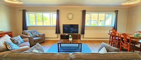 A living room with a sofa, TV, and dining table.