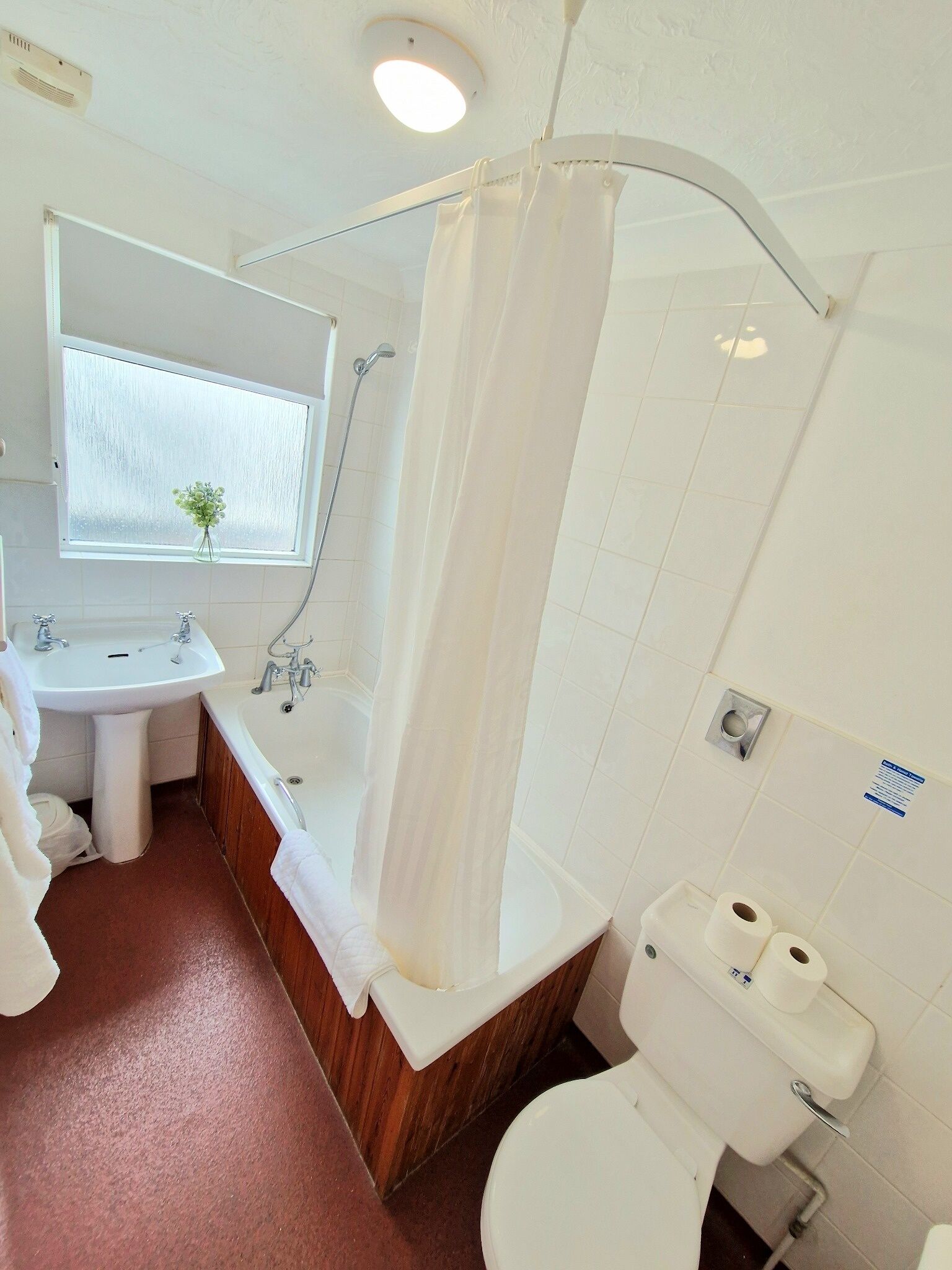 A bathroom with a sink, bathtub, toilet, and shower curtain.
