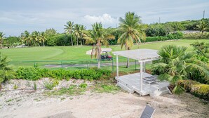A golf course with a pavilion, palm trees, and a clear sky.