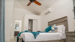 A bedroom with a bed, a nightstand, a dresser, a ceiling fan, and an air conditioning unit.