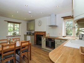 Una cocina con muebles de madera, chimenea y un reloj en la pared.