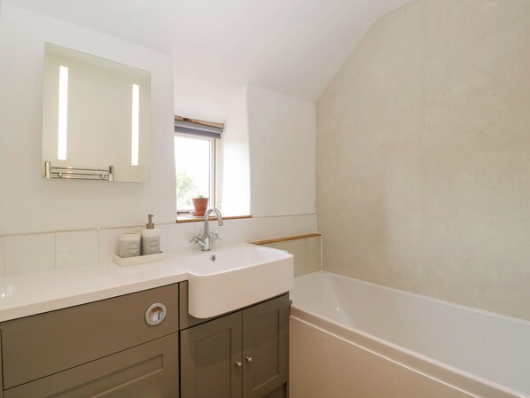 A bathroom with a white sink, mirror, and bathtub.