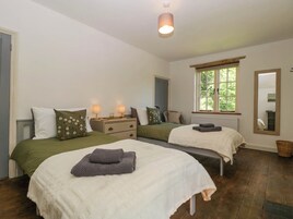 Un dormitorio con dos camas, una ventana, un espejo y una mesita de noche con lámparas.