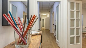 En gang med en glasvas, der indeholder blyanter, på et træbord, hvide døre og et spejl på væggen.