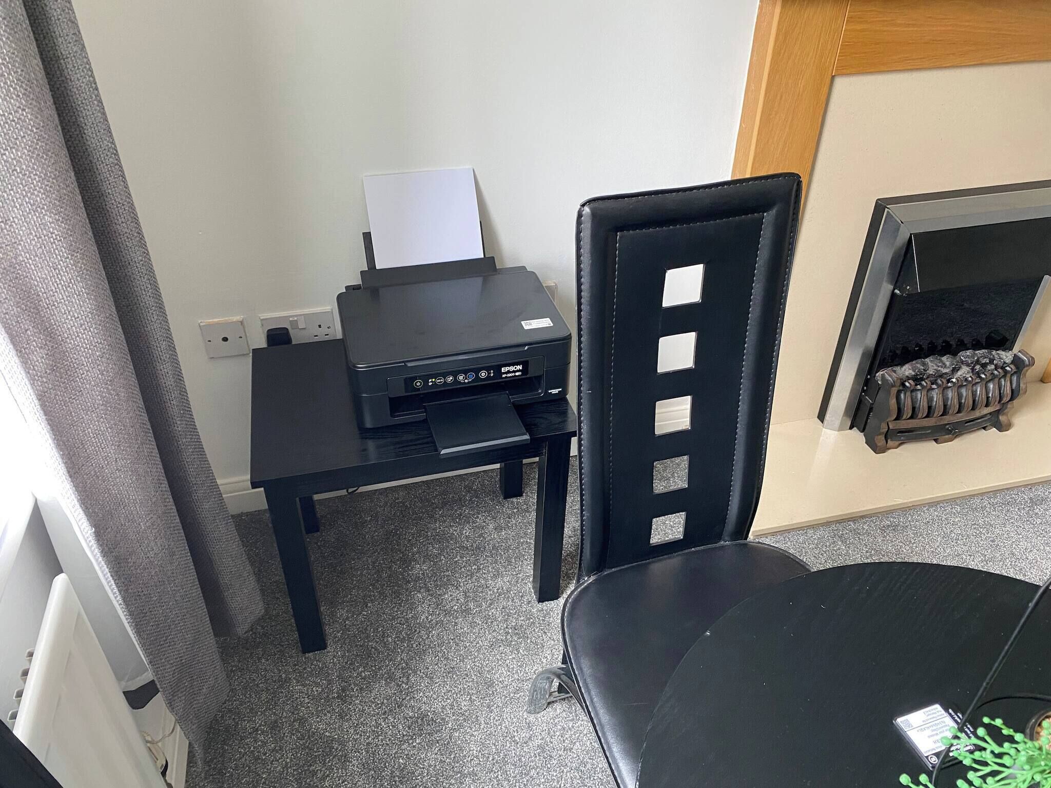 A small office space with a printer, a chair, and a table.