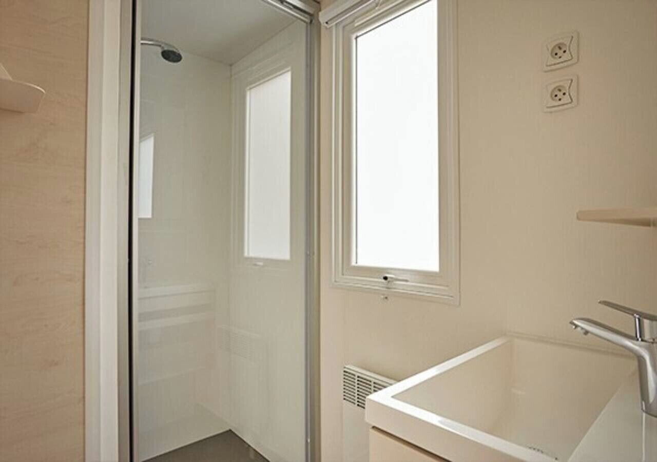 Een badkamer met een douchecabine van glas, een bad en een raam.