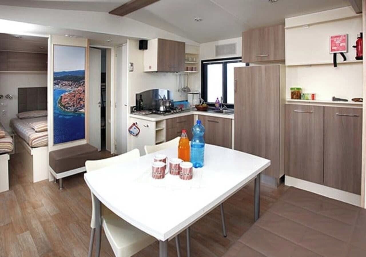 A compact kitchen with a dining table, a view through an open door, and a kitchenette area.