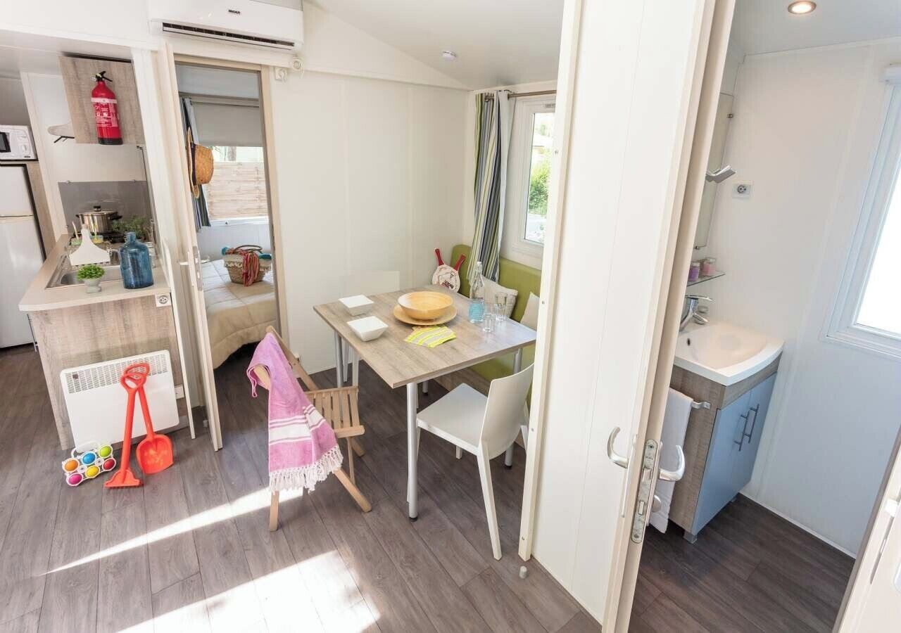 A compact living space with a kitchenette, a dining area, and a small bathroom.