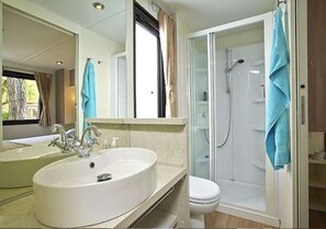 Un baño con un lavamanos grande, un inodoro y una ducha con mampara de vidrio.