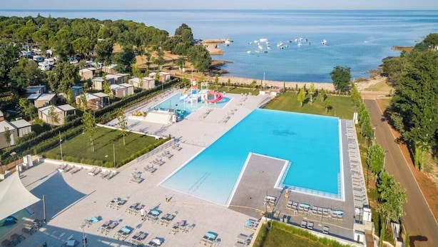 A large swimming pool with adjacent sun loungers and a children's play area. - Camping Park Umag - Eurocamp (Brtonigla)