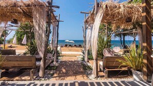 A beachside walkway with wooden benches and thatched umbrellas, leading to a beach. - Camping Park Umag - Eurocamp (Brtonigla)