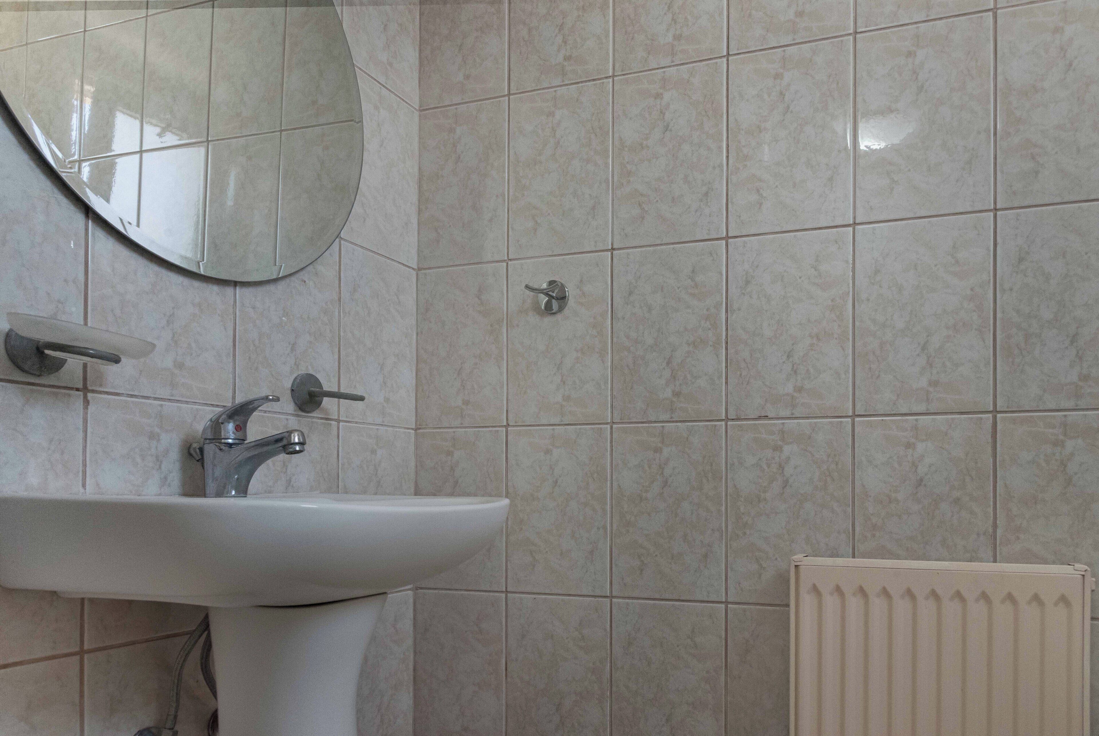 Ein Badezimmer mit Waschbecken, Spiegel und Heizkörper.