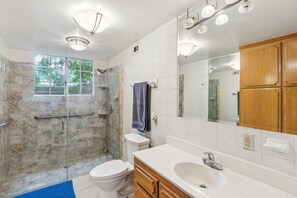 A modern bathroom with a glass-enclosed shower, a toilet, a sink, and wooden cabinets. - Russell House Near Hollywood & Griffith Park 3 Bedroom Home (Los Angeles)