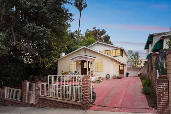 A two-story house with a red driveway, a white fence, and a brick wall. - Russell House Near Hollywood & Griffith Park 3 Bedroom Home (Los Angeles)