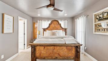 A bedroom with a wooden bed, a ceiling fan, and a sign on the wall.