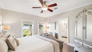 A bedroom with a large bed, a ceiling fan, a dresser, and a bathroom visible through an open door. - Rooftop Terrace | Garage | Near Beach (Santa Rosa Beach)