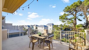 A balcony with a table and chairs, overlooking a residential area with houses and a tree. - Rooftop Terrace | Garage | Near Beach (Santa Rosa Beach)