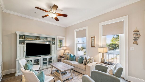 A living room with a television, seating, a ceiling fan, and a window with a view. - Rooftop Terrace | Garage | Near Beach (Santa Rosa Beach)