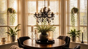 A dining area with a round table, chairs, a chandelier, potted plants, and a window with blinds. - Detached house with terraces and garden. Close to the sea and the town center (Svelvik)