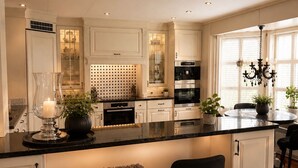 A kitchen with white cabinetry, a central island with stools, a chandelier, and a window with blinds. - Detached house with terraces and garden. Close to the sea and the town center (Svelvik)