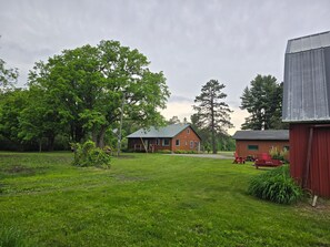 Un cadre rural avec une maison, une grange et un grand arbre.