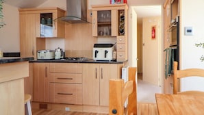 A modern kitchen with wooden cabinets, a gas stove, and a built-in oven. - 152 Central Park (Prestatyn)