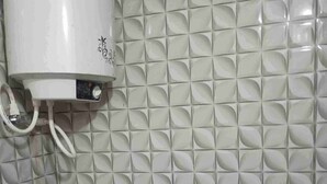 Une salle de bain avec un mur recouvert de carreaux blancs formant un motif géométrique.