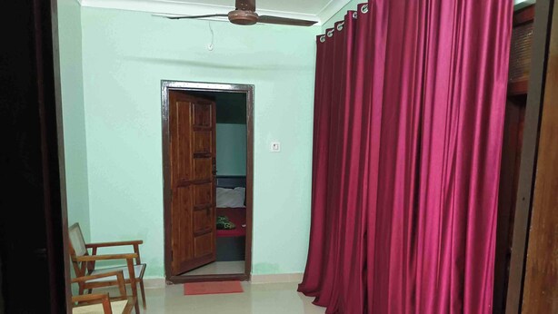 Une pièce avec une porte en bois, un rideau rouge et un ventilateur de plafond.