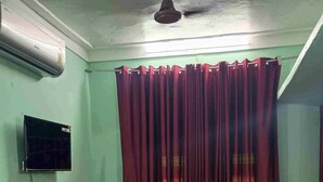 Une chambre à coucher avec un lit, un téléviseur fixé au mur et un ventilateur de plafond.