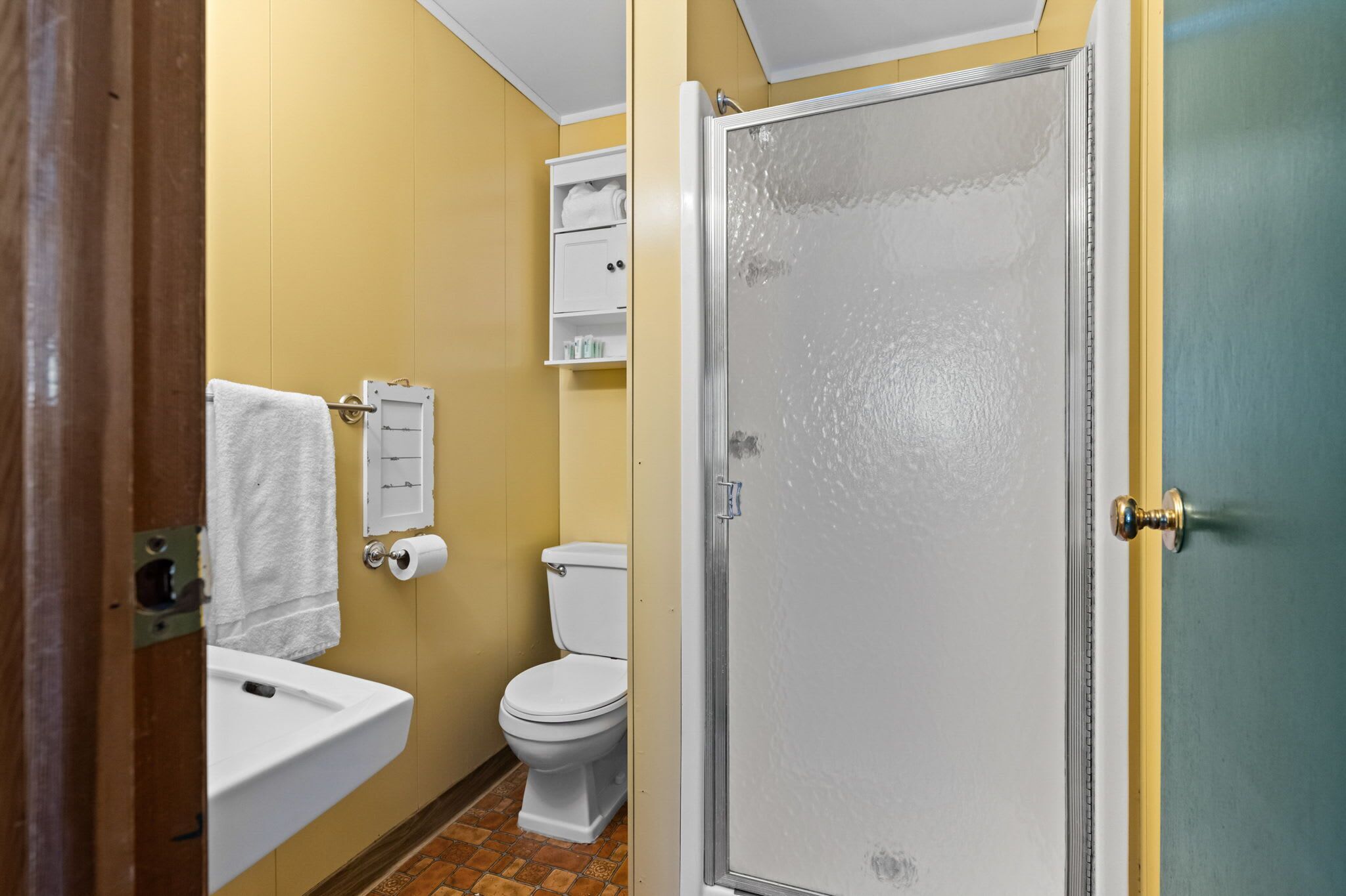 A bathroom with a toilet, sink, and shower.
