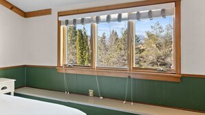 Una habitación con un amplio ventanal, vigas de madera y una pared verde.