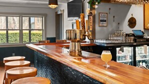 A bar area with a wooden counter, stools, and a beer tap.