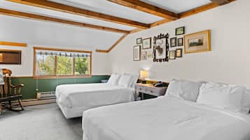 Quarto com duas camas, uma cadeira de balanço, escrivaninha com luminária e janela com persianas.