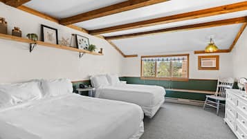 Une chambre avec deux lits, des poutres en bois, une fenêtre donnant sur un beau paysage, un bureau et une chaise.