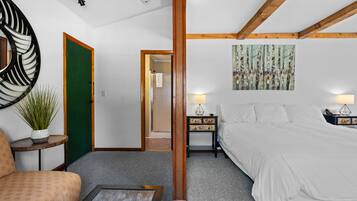 Une chambre d’hôtel avec un grand lit, une porte verte, un miroir rond, un tableau et une petite table avec une lampe.