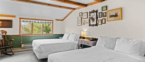 A room with two beds, a rocking chair, a desk with a lamp, and a window with blinds.