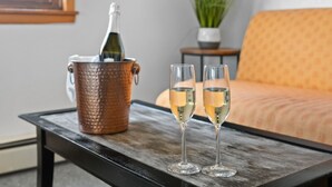 Una mesa de madera con un balde de cobre que contiene una botella y dos copas de vino blanco.